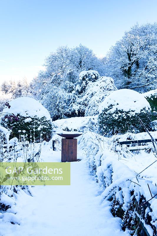 The Front Garden with bird bath on column of oak in snow. Veddw House Garden, Monmouthshire, Wales, UK. The garden was created since 1987 by garden writer Anne Wareham and her husband, photographer Charles Hawes. The garden opens to regularly to the public in the summer months.