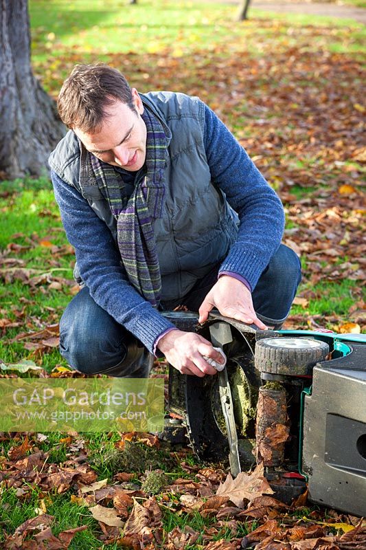 Cleaning lawnmower blades with a rag in autumn, November