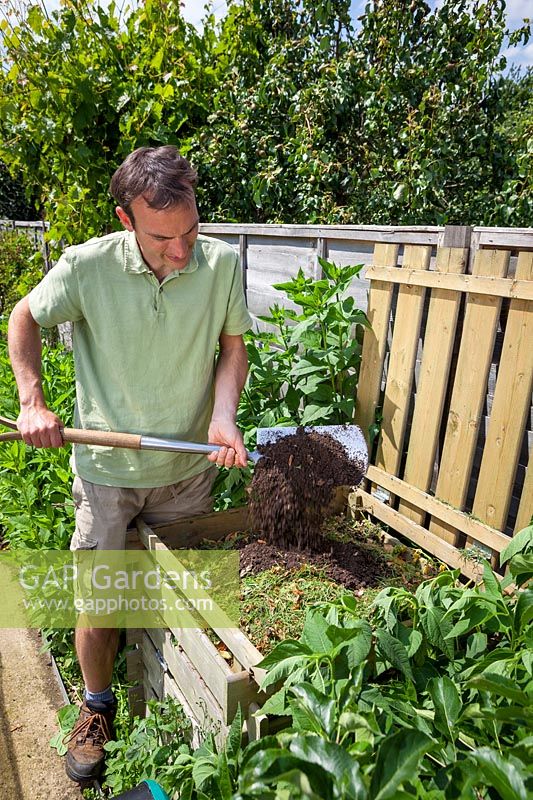 Adding soil to grass clippings in compost to maintain balance and help rot, June 