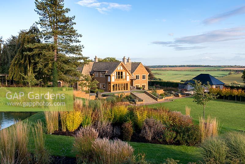 Prairie style beds with modern Arts and Crafts style house in backdrop of Welland Valley.