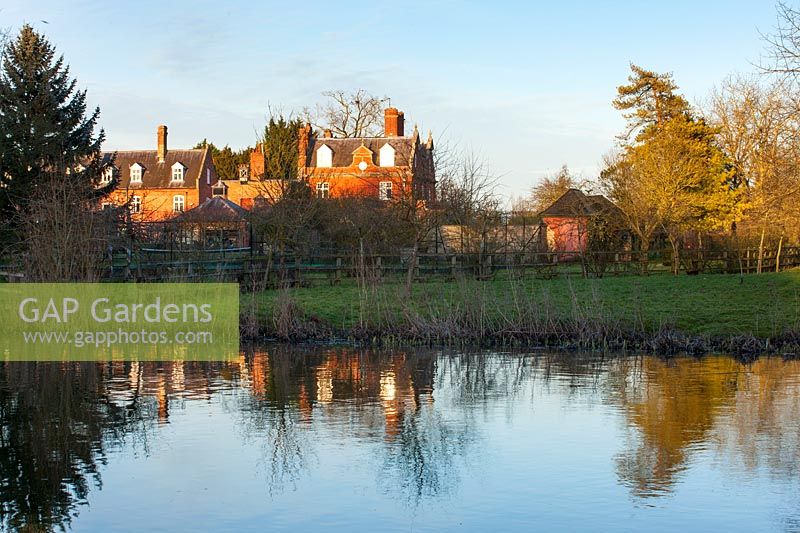 Houses reflected in lake, Chippenham Park, Cambridgeshire.