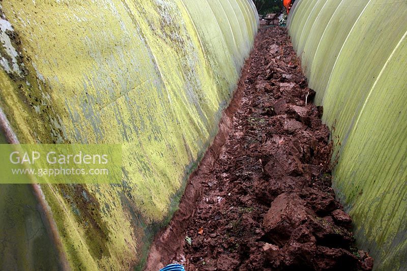 Replacing the polythene cover of a polytunnel - digging out the trench in which the old sheet is buried