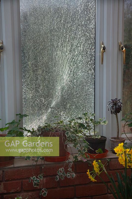 Broken conservatory window caused by stone thrown up by rotary mower