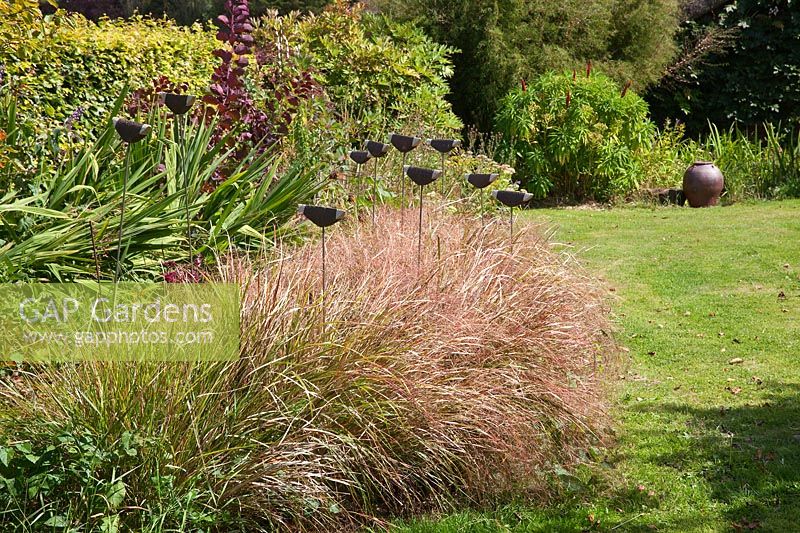 Pottery finials amongst plants in the Garden Pottery of Jonathan Garratt in Dorset