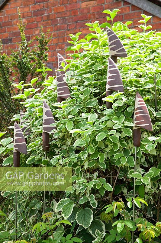 Pottery finials amongst plants in the Garden Pottery of Jonathan Garratt in Dorset