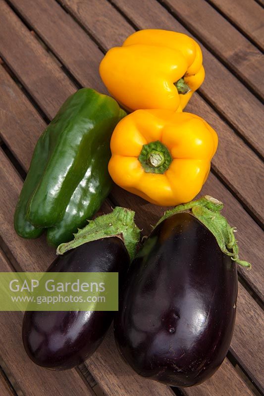 Colourful vegetables - Peppers and Aubergines - outdoors on a wooden table