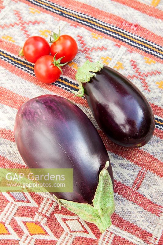 Fresh Aubergines and cherry tomatoes on a kilim covered table