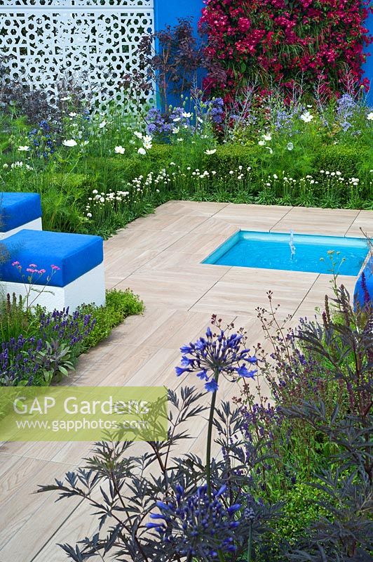 Paving surrounding a small rectangular pool in a blue and white themed Mediterranean style garden