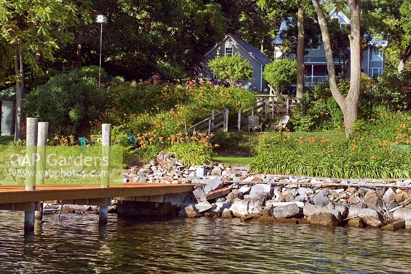 Wooden jetty leading from lake edge and American terraced garden