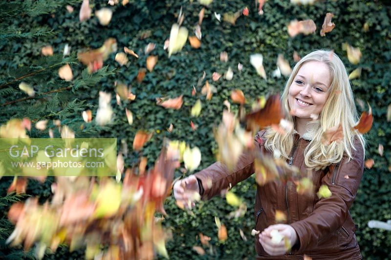 Girl throwing autumn leaves