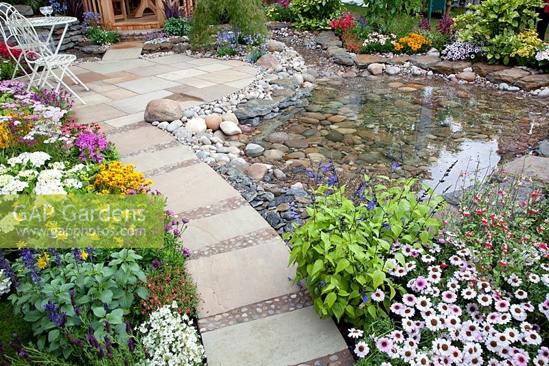 Patio with pond, perennial border and iron garden furniture