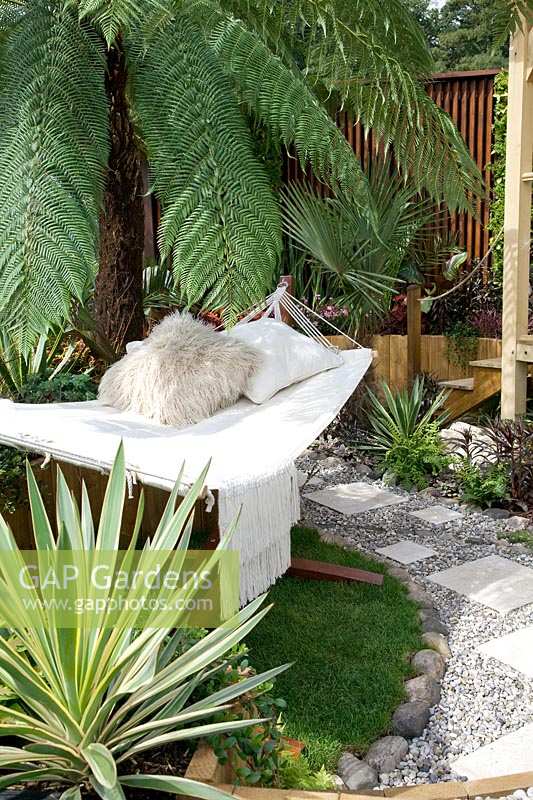 Tropical garden with hammock, Dracaena and palm trees