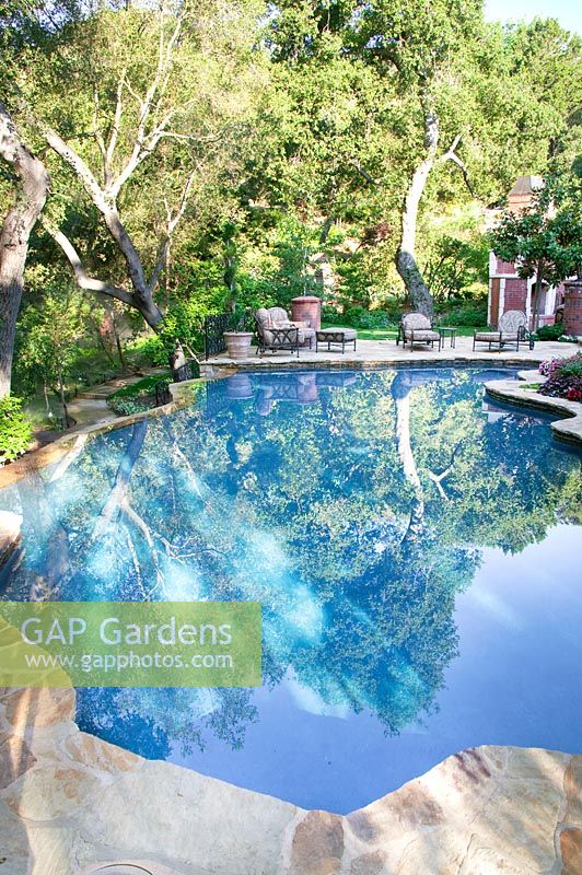 Swimming pool with iron garden furniture, framed with natural stone