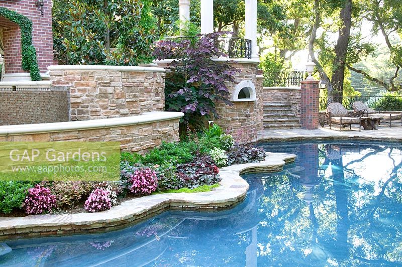 Swimming pool framed with natural stone, border with perennials and annuals