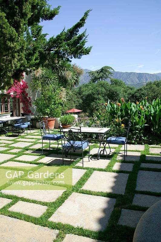 Terrace with natural stone slabs, garden furniture, container plantings, Canna and perennials