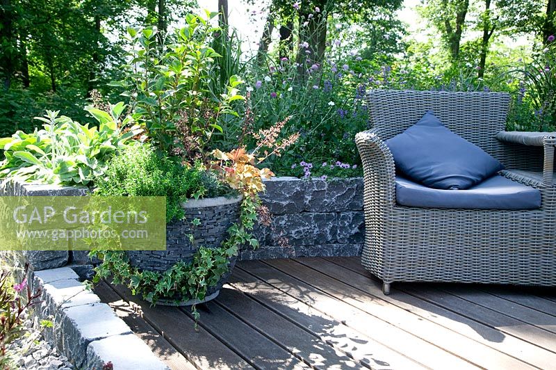 Terrace with plant container, perennial border and garden furniture