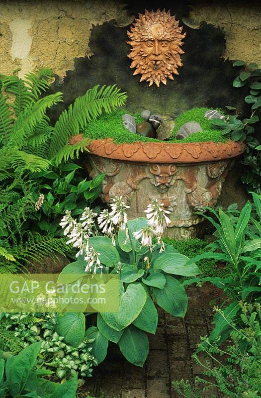 large Whichford terra cotta container as water feature with sun face plaque Mind your own business and pebbles