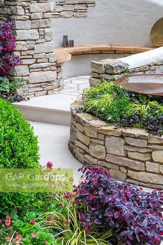 Miles Stone: The Kingston Maurward Garden, RHS Chelsea Flower Show 2019 - View over raised borders to a secluded seating area - Design: Michelle Brown, Sponsors: Miles Stone, Kingston Maurward College, Goulds Garden Centre, Greg and Will Wilkes Landscaping