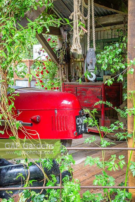 Old red classic Morgan sports car in outbuilding. The High Maintenance Garden for MND Association. Designer: Sue Hayward. Sponsor: MND Association.