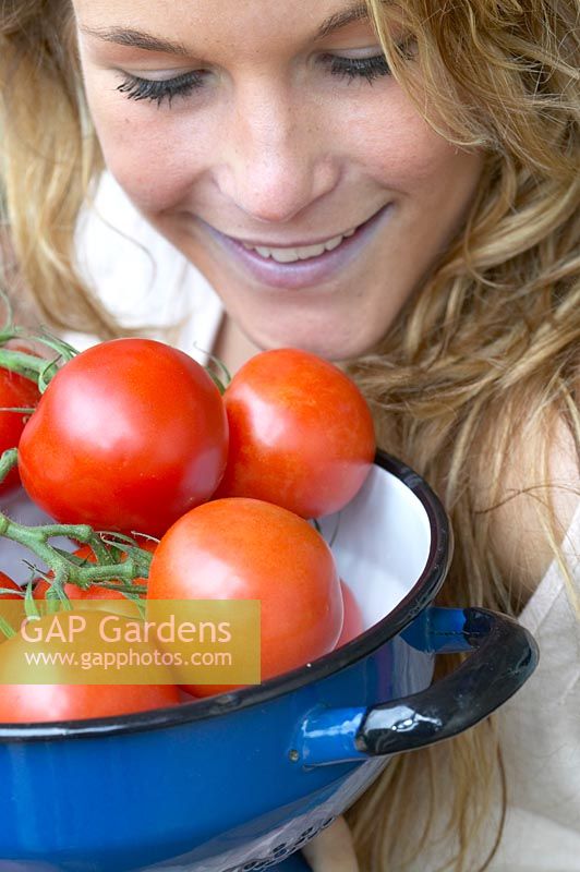 Woman holding colander with tomatoes