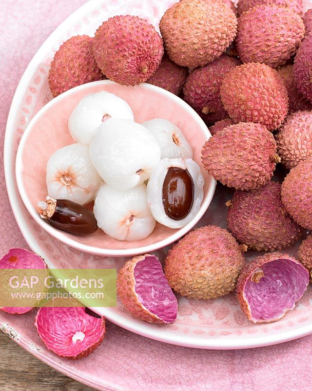 A pile of Litchi chinensis, Lychee, in a pink patterned bowl and plate set. 