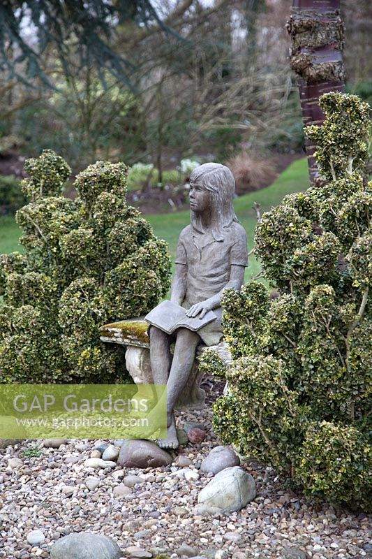 Sculpture of a girl, set amongst cloud shaped shrubs 