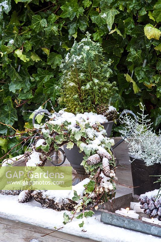 Close up of winter garden decoration on table with wreath, cones and evergreens.