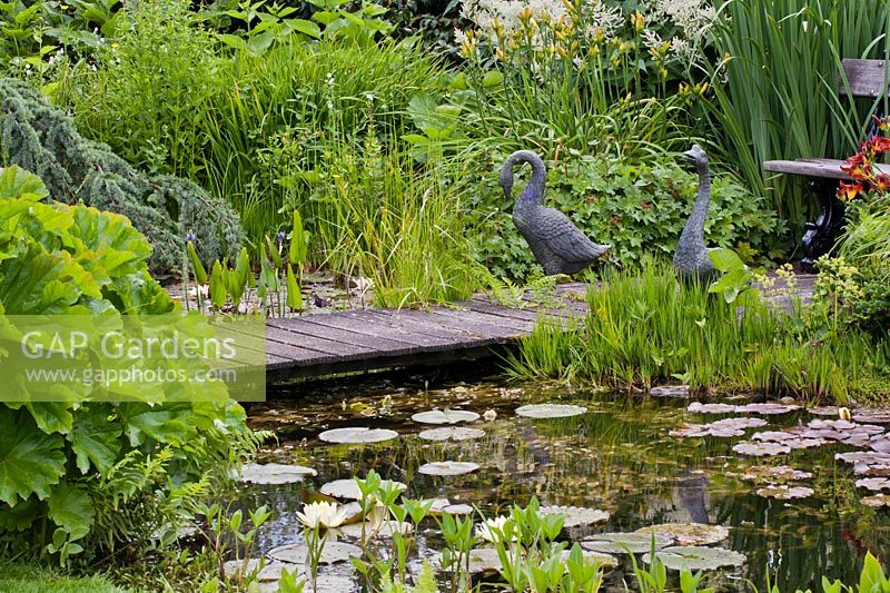 Geese statues on jetty in pond area.