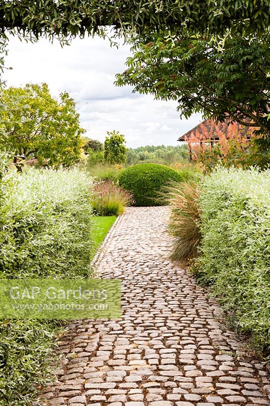 View down cobbled stone path in The Walled Garden at Bury Court Gardens, Hampshire, UK. 