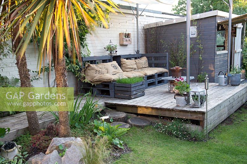 A covered decked seating area with furniture made from reused pallets.
