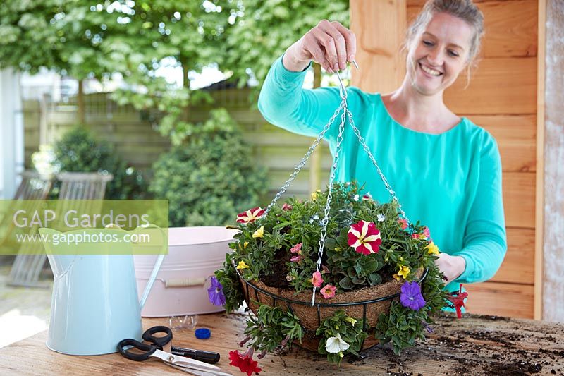 Lady lifting chain to admire hanging basket after creation