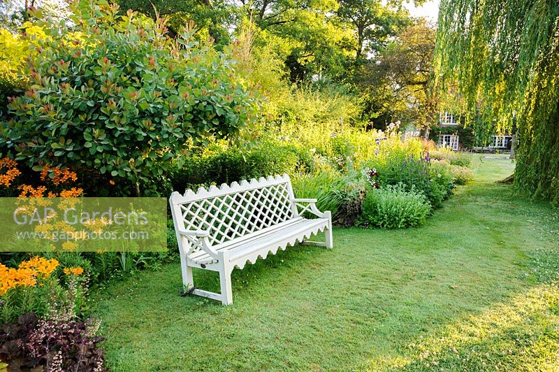 Bench set into the herbaceous border. Dipley Mill, Hartley Wintney, Hants, UK