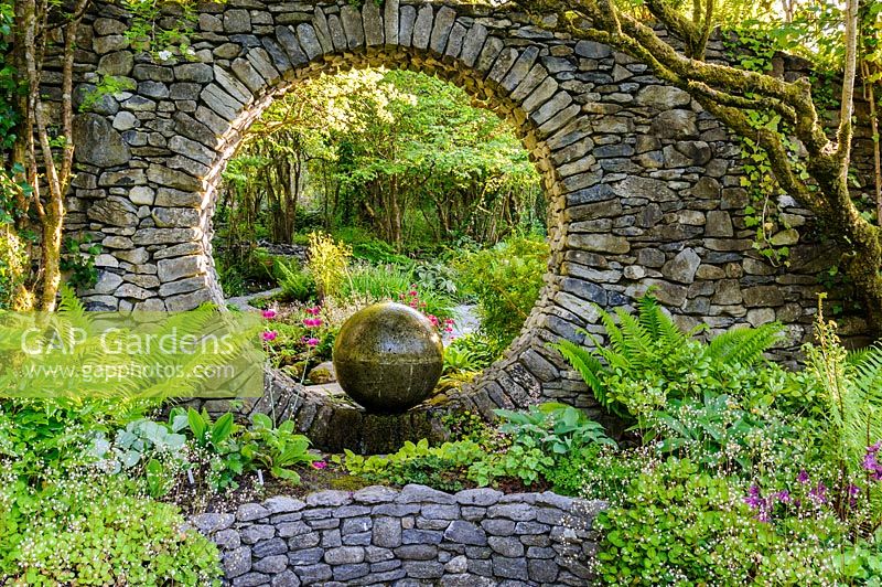 Moon Window in stone wall with cast concrete water feature with shade planting. Fanore, Ireland