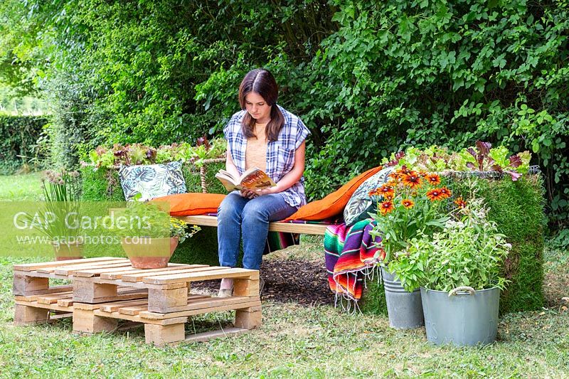 Woman seated on living gabion bench reading a book