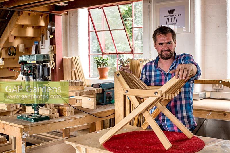 Chris Punch, garden furniture designer in his workshop assembling a footstool from component parts