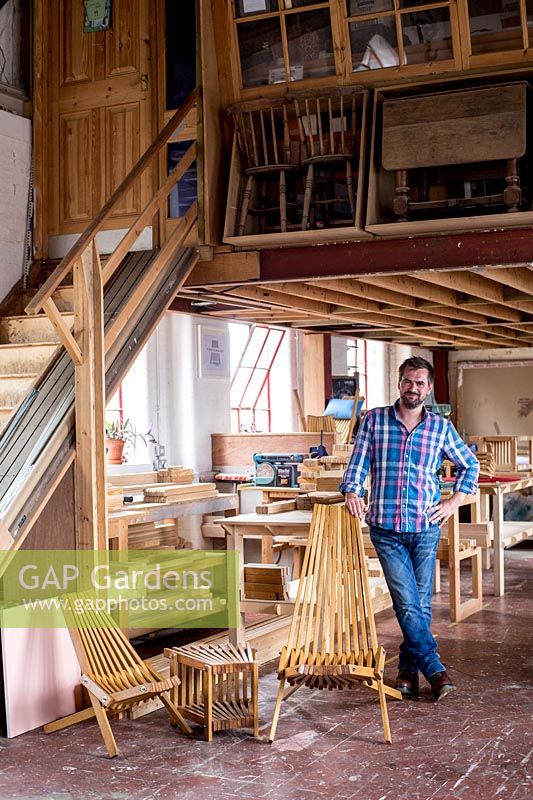 Chris Punch, garden furniture designer in his workshop, with the range of chairs he produces