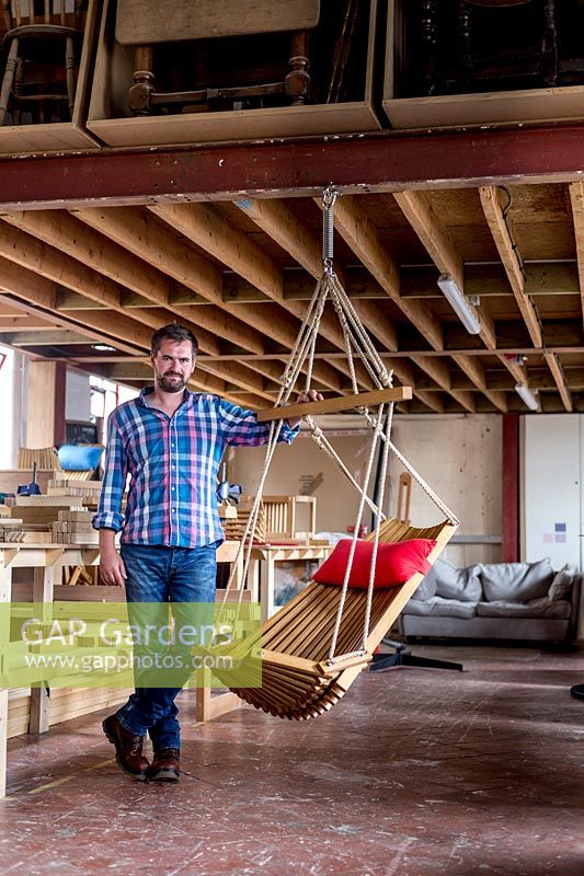 Chris Punch, garden furniture designer, in his workshop, with the range of chairs he produces. 