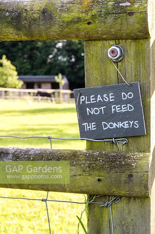 Sign requesting visitors not to feed the donkeys on the fence of their paddock. 