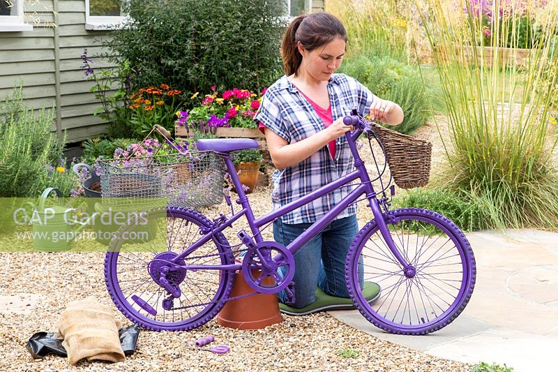 Woman fixing woven basket to handlebars with string
