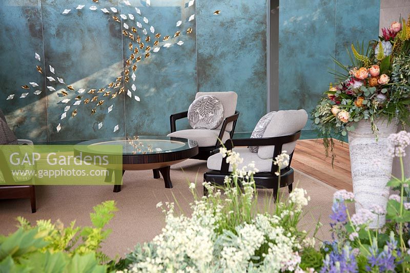 The Morgan Stanley Garden for the NSPCC - Seating in garden room with wall decoration reflected in table top - Sponsor: Morgan Stanley - RHS Chelsea Flower Show 2018
