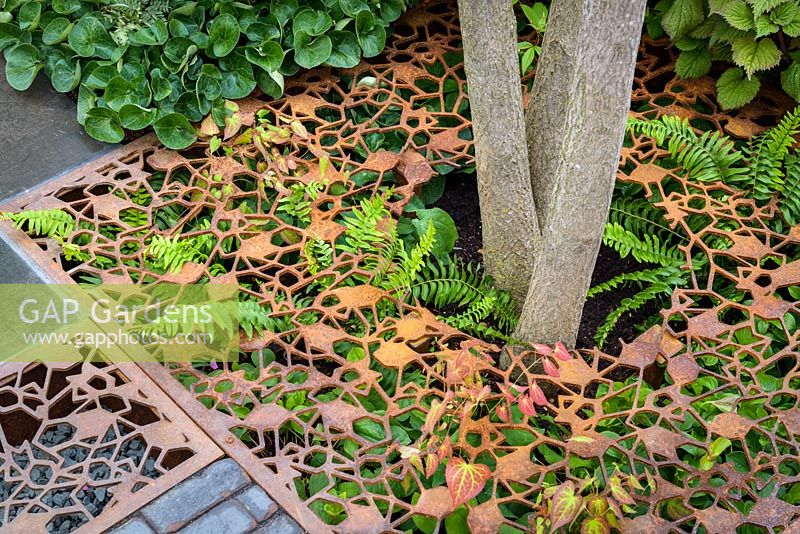 Leaf-shaped permeable paving made of laser cut metal grids over planting of ferns. Urban Flow garden, Sponsor: Thames Water, RHS Chelsea Flower Show, 2018.
