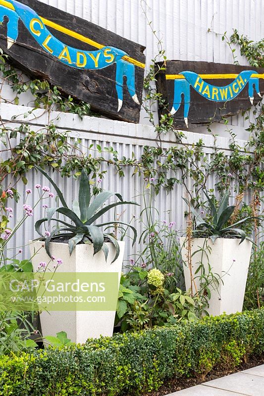 Tall fencing providing privacy and decorated with name board from ship