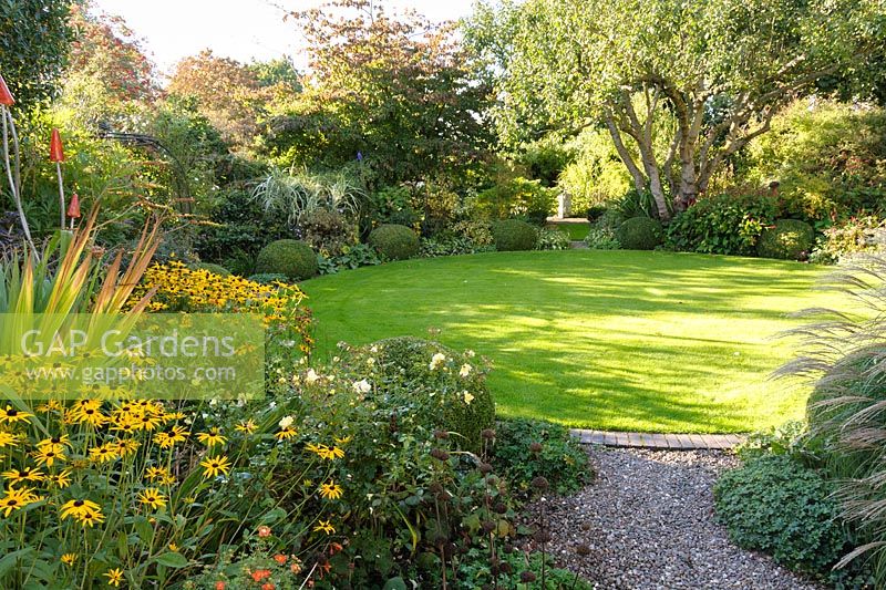 Circular lawn with mixed green foliage planting in beds