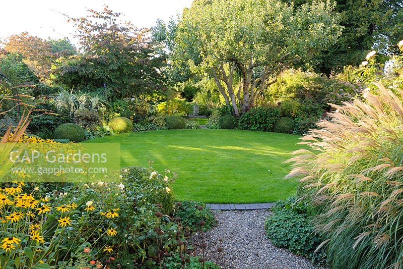 Circular lawn with beds of herbaceous perennials and grasses - Shropshire, UK