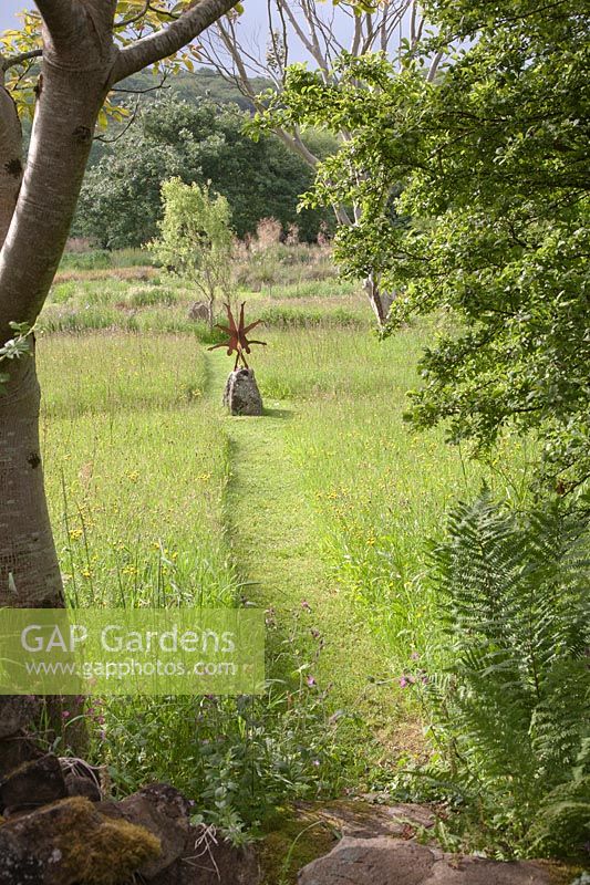 Metal sculpture of Acrobats 'Head over Heels' beside grassy path at Dyffryn Fernant, UK