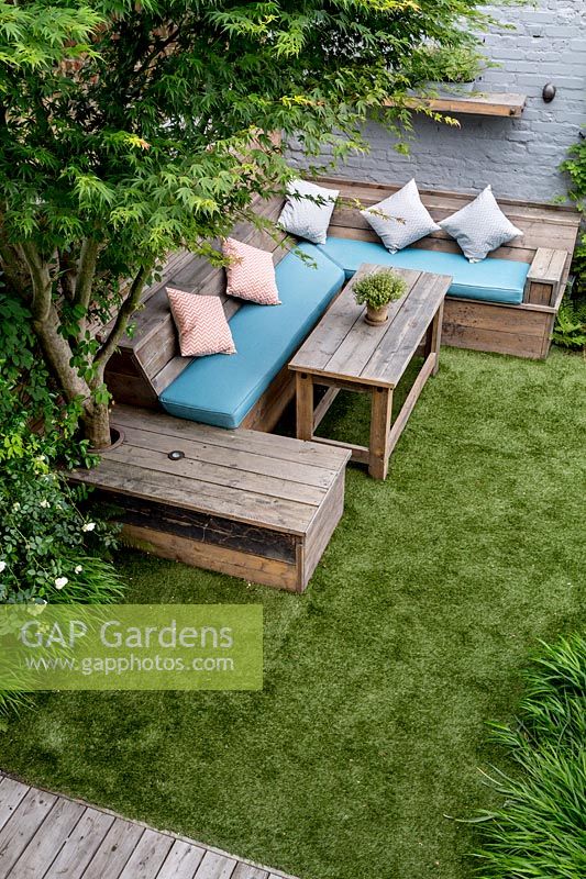 Courtyard garden in West London with artificial lawn and reclaimed scaffold board seating 