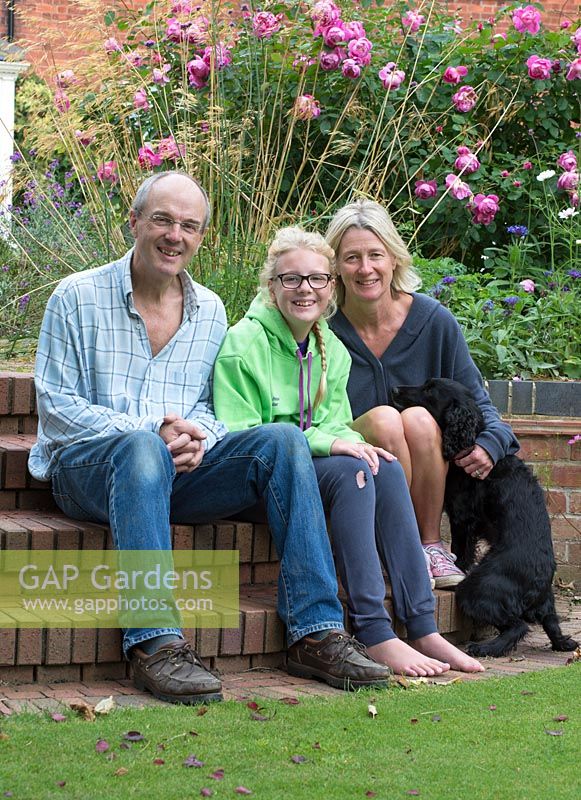 Portrait of garden owners Nigel, Tilly and Alice Gray with Hebe the dog in garden. 