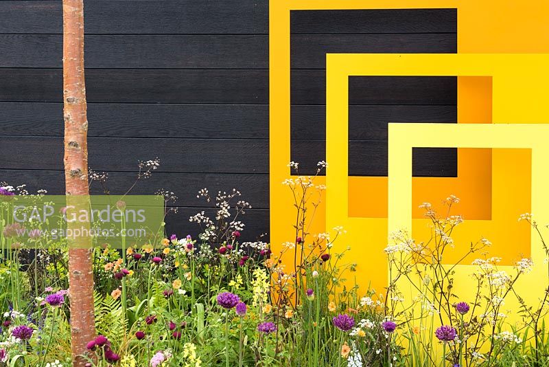 Yellow steel sculptural panels with black fence and meadow-style planting - 'Urban Oasis', RHS Malvern Spring Festival 2018.