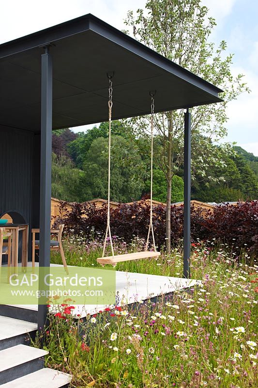 Pavilion with swing in meadow of Achillea, Lychnis and ox-eye daisy. 'A Family Garden' 
