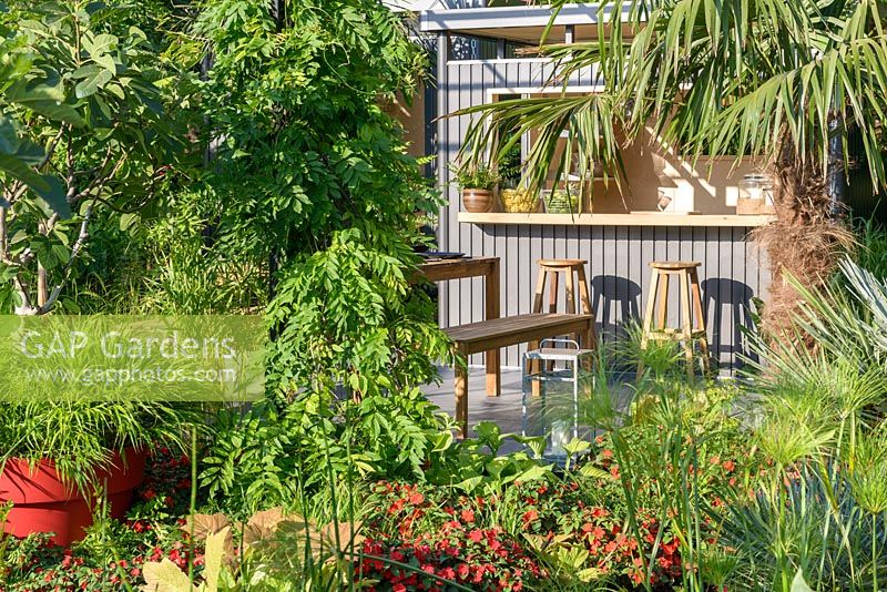 Highline metal shed and wooden seats. 'B and Q Bursting Busy Lizzie' Garden, RHS Hampton Flower Show, 2018